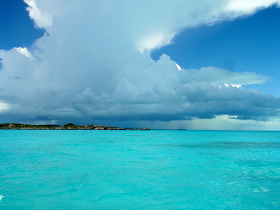 A passing storm with heavy dark clouds intensifies the turquoise colour of the ocean at one of the cays of the southside of Providenciales