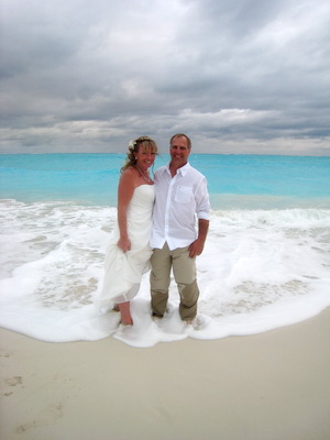 The bride and groom stand surrounded by the foaming waves at Leeward beach
