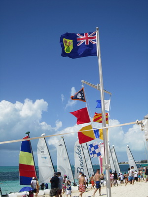 The Turks and Caicos Island Flag flies high as the Hobie Cats are waiting and lined up along the beach